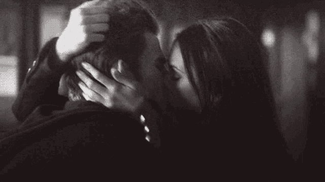 a man and a woman kissing in a black and white photo .