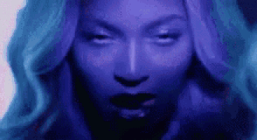 a close up of a woman 's face with blue hair and black lips .