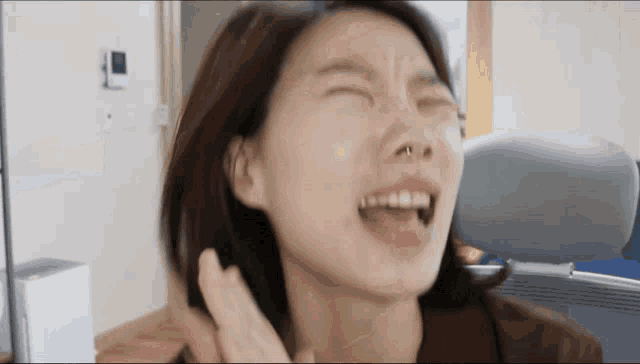 a woman with a nose ring is making a face with her eyes closed