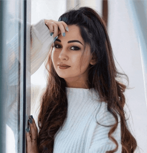 a woman in a white sweater leans on a window