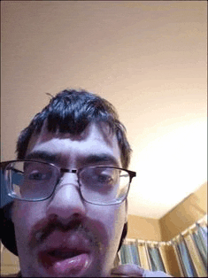 a man with glasses and a mustache is licking his lips .