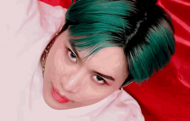 a close up of a person with green hair looking at the camera