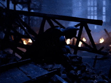 a silhouette of a man in a batman costume sitting on a pile of rocks
