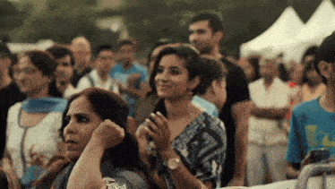 a woman covering her ears in a crowd with a man in a blue shirt with the word reebok on it