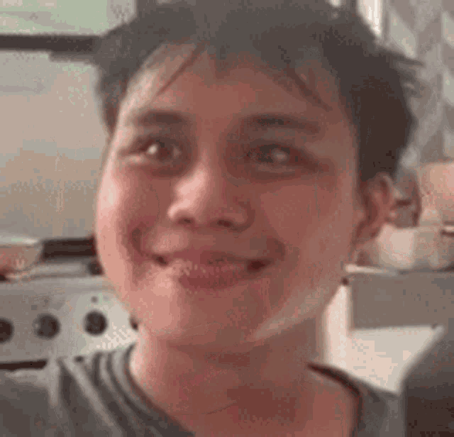 a young man is smiling and looking at the camera while standing in a kitchen .