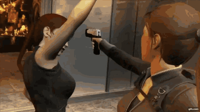 a woman is pointing a gun at another woman who is holding her arm up