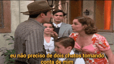 a man in a hat is talking to a woman in a pink dress while another man looks on