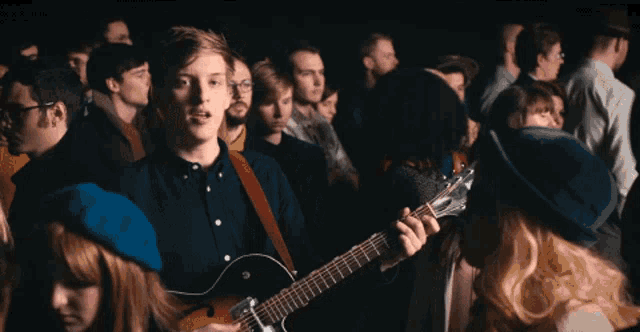 a man playing a guitar in a crowd of people