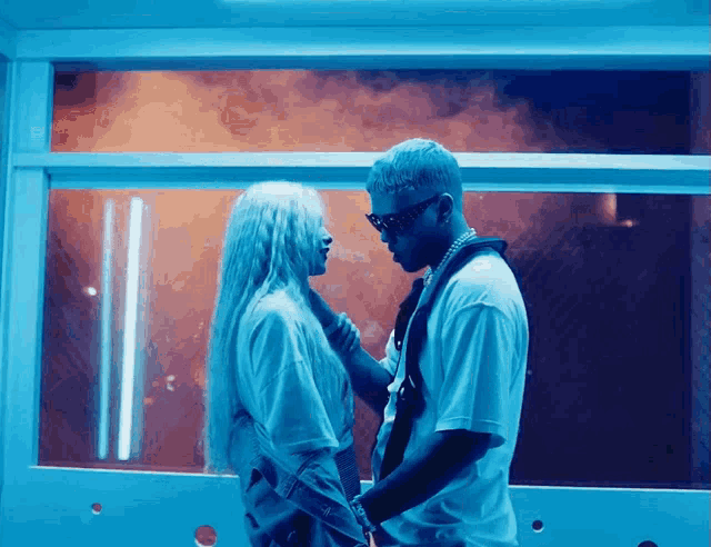 a man and woman are kissing in front of a window