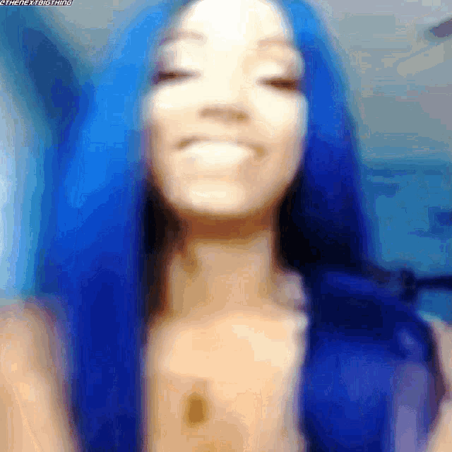 a woman with blue hair is smiling with her eyes closed .