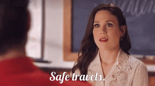 a woman says safe travels while talking to a man in front of a blackboard