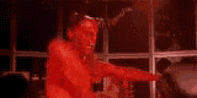 a devil with horns is standing in front of a window .