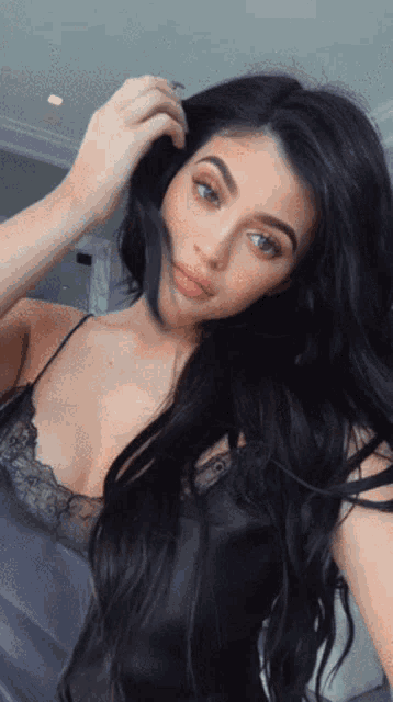 a woman with long black hair is taking a selfie with her hand in her hair