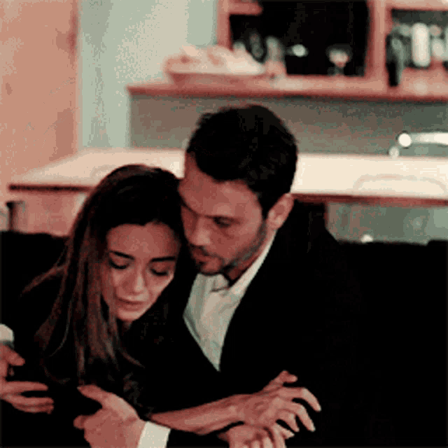 a man and a woman are sitting on a couch and hugging each other