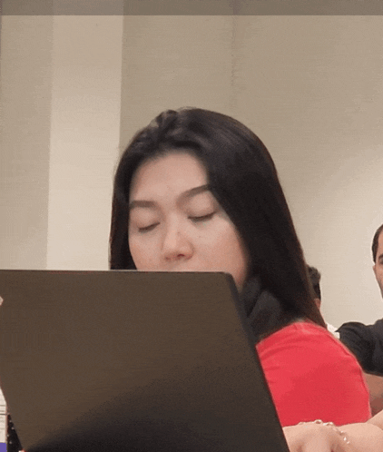 a woman in a red shirt is using a laptop computer