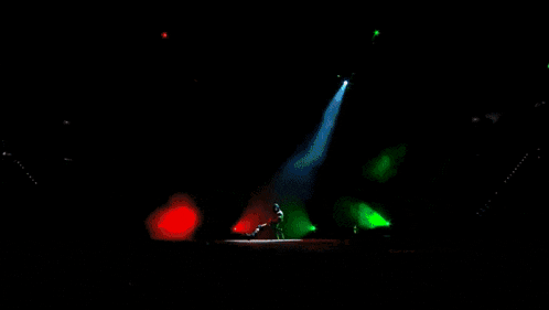 a naked man is standing on a stage in front of green lights