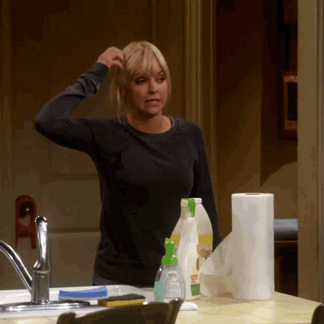 a woman standing in front of a kitchen counter with cleaning supplies