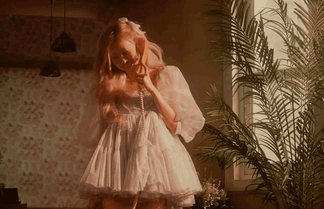 a woman in a white dress talks on a phone