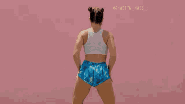 a woman in a white crop top and blue shorts is dancing .