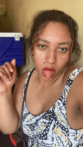 a woman sticking her tongue out while wearing a black and white tank top
