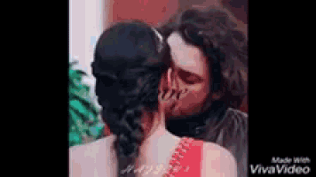 a man and a woman are kissing in front of a tree .