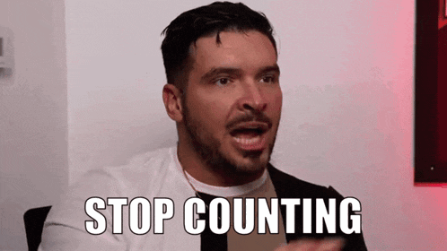 a man with a beard is sitting in front of a wall and says `` stop counting '' .