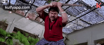 a man in a red shirt is holding a stick in his hand .
