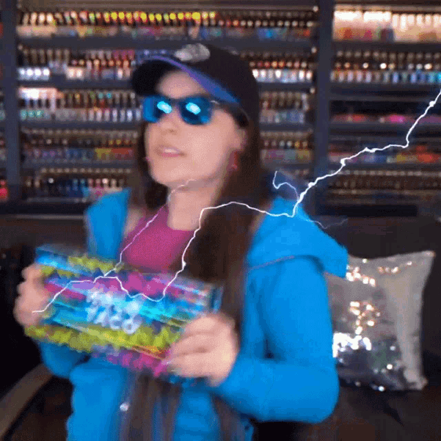 a woman wearing sunglasses and a hat is holding a box that says ' taco ' on it