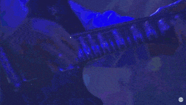 a close up of a person playing a guitar with a purple background