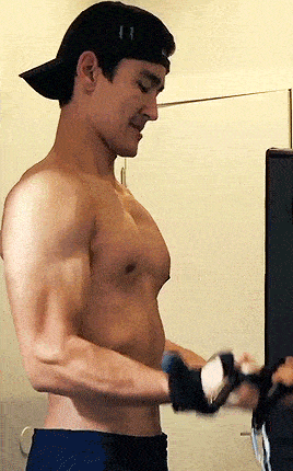 a shirtless man wearing a black hat and gloves is working out