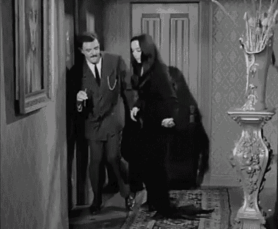 a man in a suit and tie is standing next to a woman in a black dress .