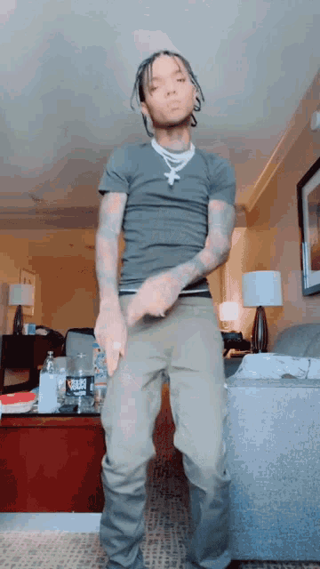 a man in a grey shirt is dancing in a room