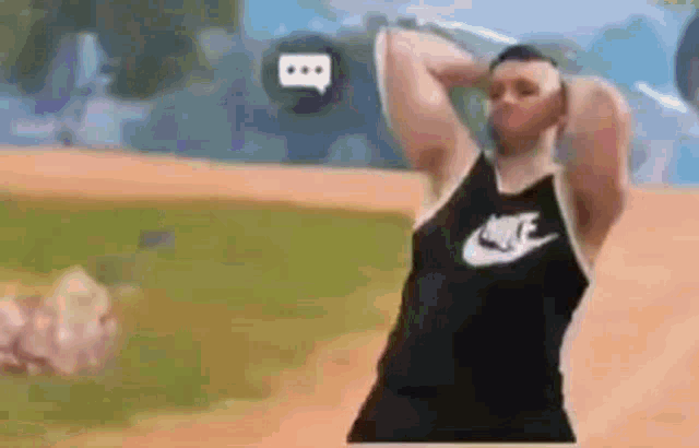 a man wearing a nike tank top is standing on a baseball field .