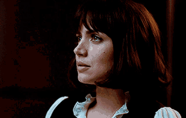 a woman with short brown hair is wearing a white shirt
