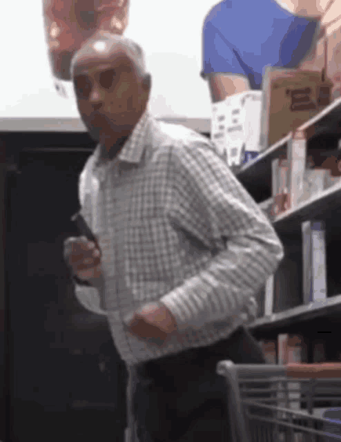 a man in a plaid shirt stands in front of a shelf with a box of peanut butter on it