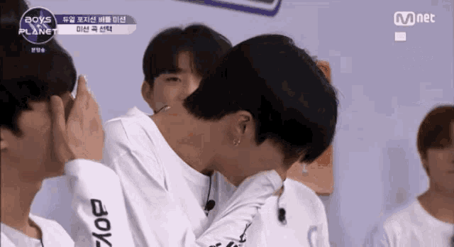 a group of boys are sitting in front of a mnet sign