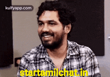 a man wearing a plaid shirt is smiling and says starttamilchat.in .