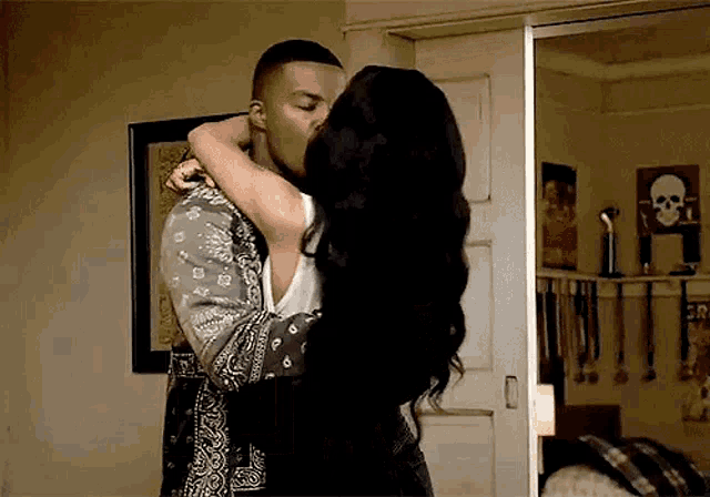 a man and a woman are kissing in a bedroom in front of a mirror .