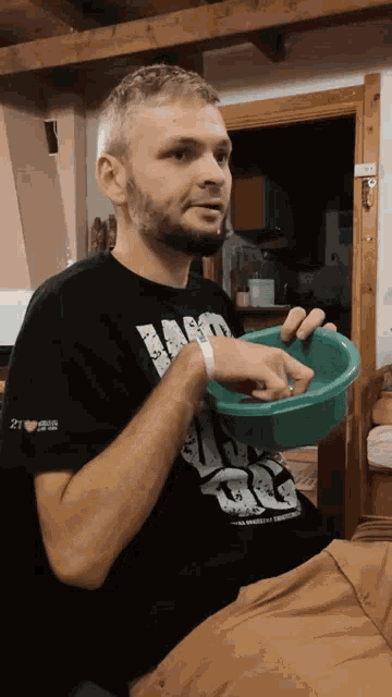 a man wearing a black shirt that says 21 on the sleeve is holding a green bowl