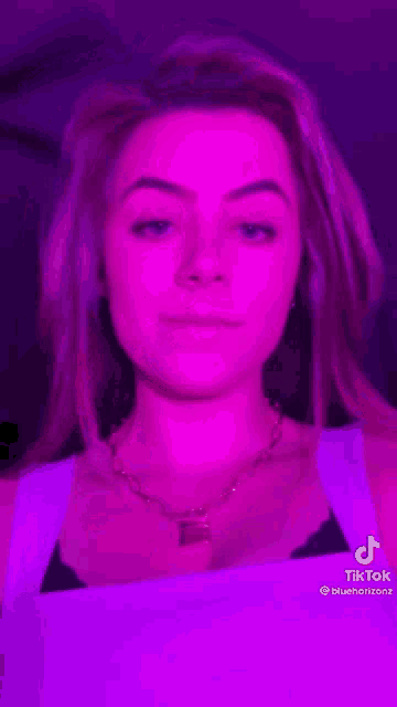 a woman is holding a lollipop in her mouth in front of a purple light .