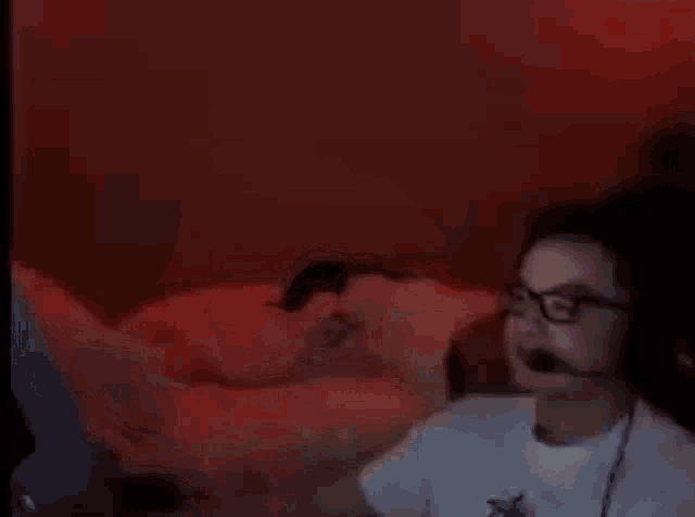 a blurry picture of a man in a white shirt standing next to a bed .