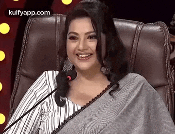 a woman is sitting in a chair holding a microphone and smiling .