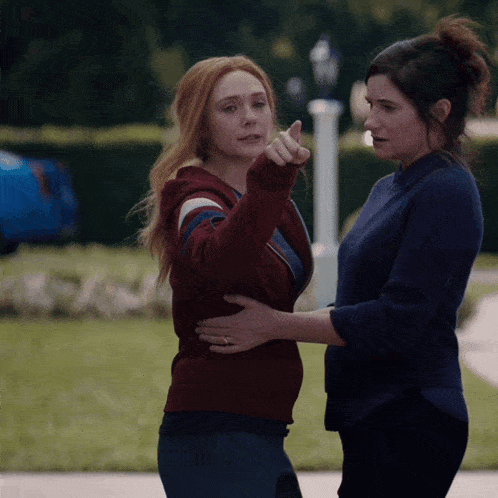 two women are standing next to each other one is pointing