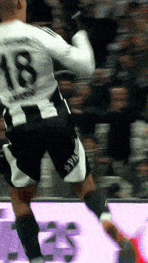 a soccer player with the number 18 on his jersey is jumping in the air