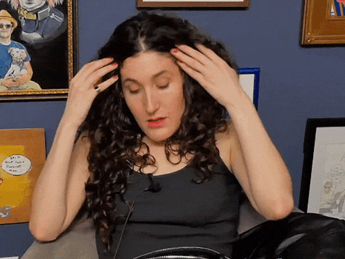 a woman adjusts her hair in front of a framed picture of a man and a dog