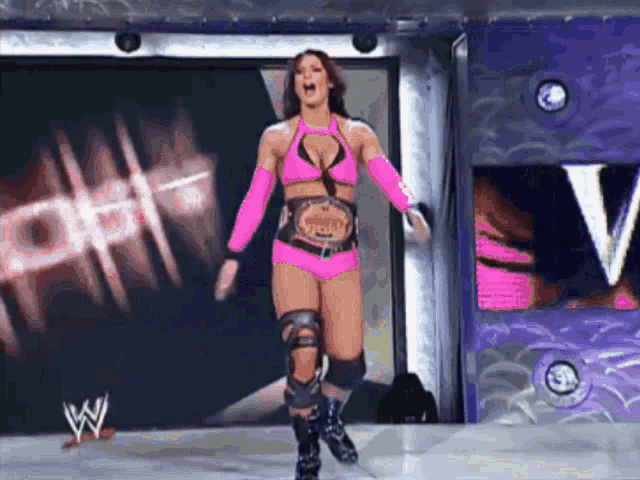 a female wrestler in a pink outfit with a belt that says world heavyweight champion on it