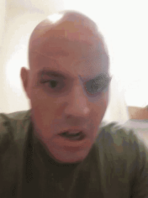 a close up of a bald man 's face with a blurred background