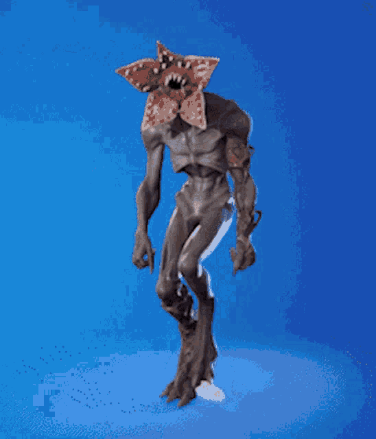 a statue of a monster with a flower on its head is standing on a blue background .