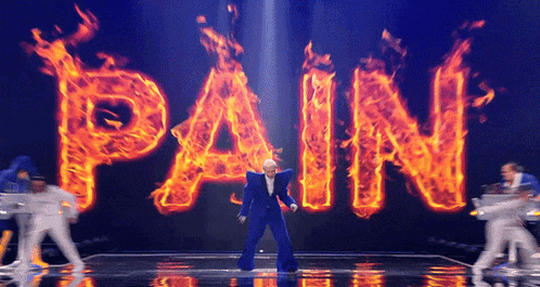 a man in a blue suit is dancing in front of the word pain that is on fire