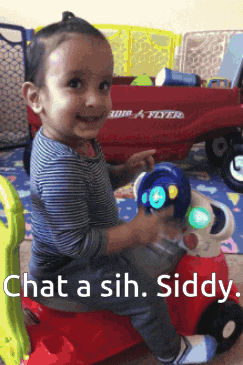 a little boy is sitting on a red toy car that says chat a sih siddy on it
